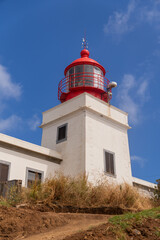 White building with a red lighthouse against a blue sky.