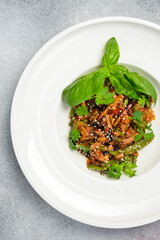 Wok salad in a round white plate. On a stone background. Close-up.