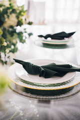Setting the festive table. empty plates with green napkins. flower arrangement