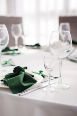 Setting the festive table. empty wine glasses and plates with green napkins.