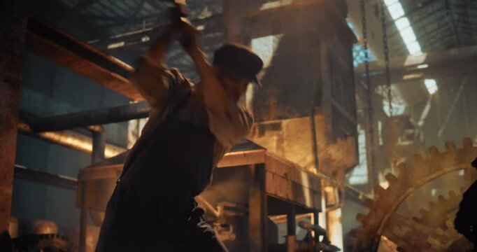 Caucasian Male Worker in Historical Ironworks Footage Using  a Sledgehammer for Work at an Iron Foundry. Man Using Brutal Physical Force and Craftsmanship of the Early Industrial Era