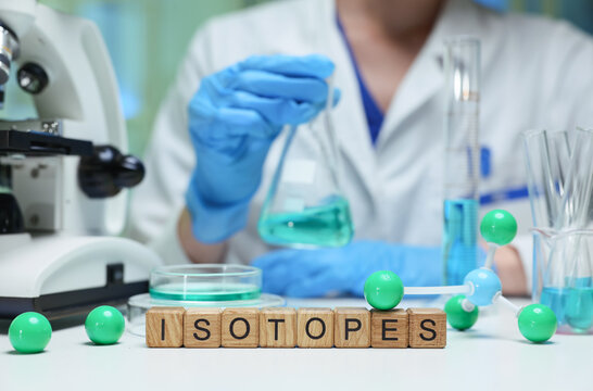 A scientist is diligently working with isotopes in a lab, using pipettes and glassware for chemistry experiments