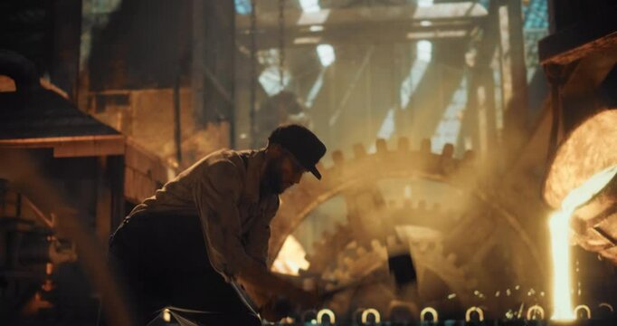 Man in Worn Work Clothes Strikes Iron with a Sledgehammer Inside a Gritty, Fire-Lit Workshop. Man s Doing Manual Labor During the Industrial Revolution. Cinematic Slow Motion Footage
