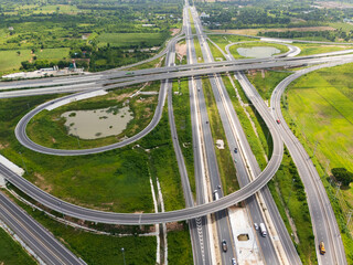 Drone shot a large highway interchange crossing over green farmlands in Thailand