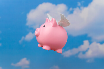 A piggy bank with small white wings flying against a blue sky. Symbolizes concepts related to money flying away, financial freedom, or the elusive nature of wealth.