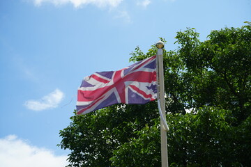 Pavilion Gardens, Buxton, England – July 8 2025: Union Jack flag waving against blue sky and...