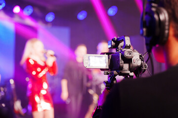 A professional videographer is filming a concert on stage. blurred stage.