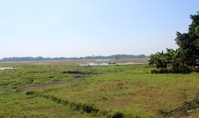 Fototapeta premium Grassy field by the reservoir. Serene landscape, vast open space. Perfect for nature, outdoor, and tranquility themes