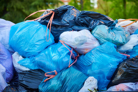 Trash bags pile up on the strret during a garbage collection strike, creating unsanitary conditions and visual clutter in a city environment