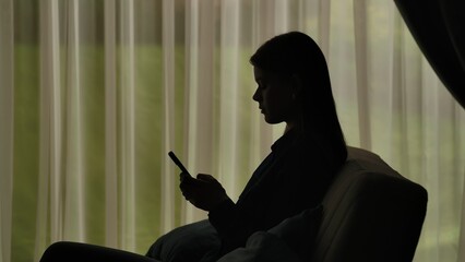 Silhouette of a Woman Using Smartphone by Window