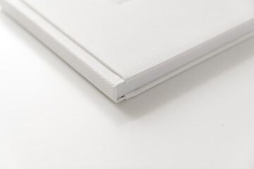 corner of book in white leather cover on white table. binding for photo album