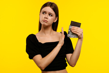 Woman Refusing Chocolate Against Bright Yellow Background