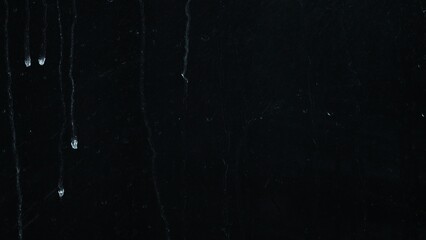 Water drops and water streaks on glass isolated on black background