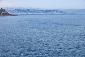 Cliffs on the Cote d'Azur, French Riviera, overlooking Cannes, with a cruise ship and snow-capped mountains in the background