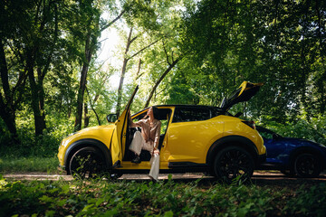 Two women are near yellow and blue cars in the forest