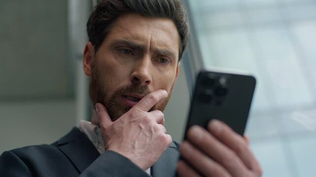 Close up Caucasian businessman business man in office worried anxiety sad thinking pensive about problem with mobile phone message bad news male employer entrepreneur with smartphone looking in window - Powered by Adobe