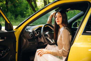 Side view, driver is sitting. Woman is with her car in the forest