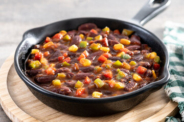 Mexican chilli beans with vegetables in iron pan on wooden table