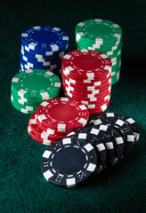 Stacks of red, blue, green, and black poker chips are arranged neatly on a green felt surface. The atmosphere suggests a lively gaming night among friends, emphasizing strategy and excitement