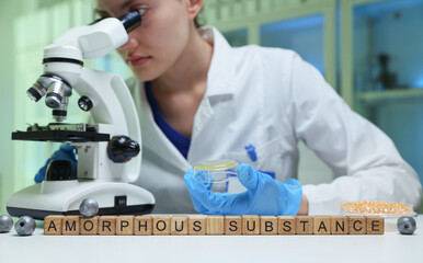 A dedicated scientist is thoroughly examining an amorphous substance using a powerful microscope in...