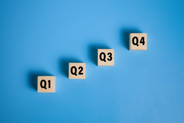 wooden cubes with q1, q2, q3, q4 symbol isolated on blue background. concept of quarterly report...