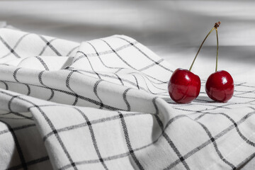 Two red cherries close-up on a checkered napkin. Selective focus.