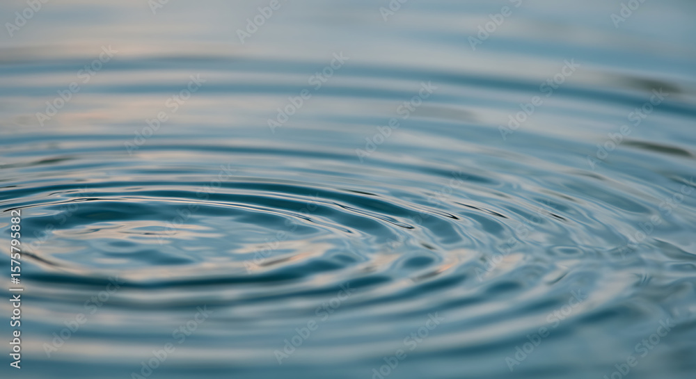 Poster gentle concentric ripples on a tranquil water surface, forming a mesmerizing circular pattern that c