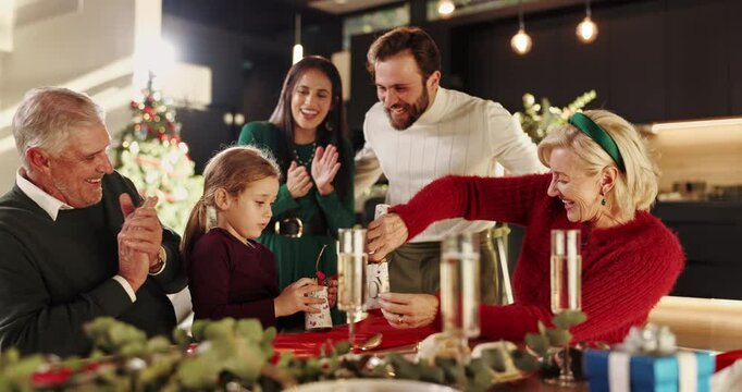 Excited, Christmas cracker and girl with big family for applause, bonding and celebration. December, holiday or festive surprise with parents, grandparents and child with social gathering in home