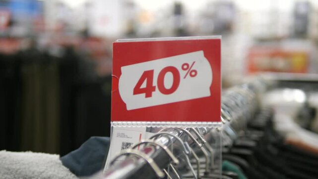 Red 40 percent off sale sign on clothing racks in a clothing store. Sale, bargains and old collection liquidation.