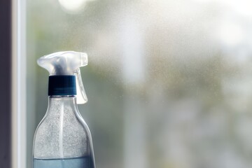 Close-up of Spray Bottle Releasing Mist Onto Window During Daytime
