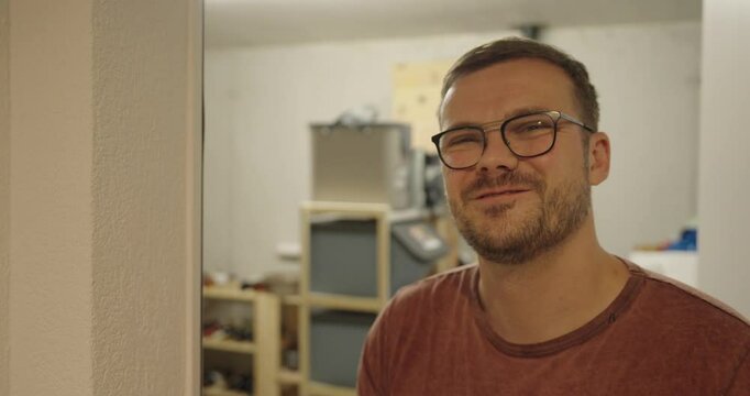 A young man in front of a warehouse or cellar laughs into the camera and is happy