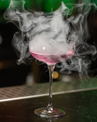This visually striking pink alcoholic cocktail in a coupe glass features a large, dome-shaped smoke...