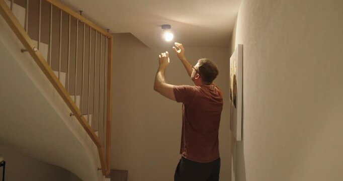 A man tries to change a light bulb but keeps getting slight electric shocks and then falls over