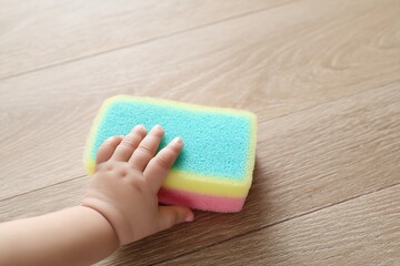 Colorful Cleaning Sponge Being Touched by a Child's Hand in a Home Setting
