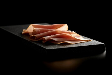 Thin Slices of Smoked Turkey Neatly Arranged on a Black Serving Board