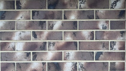 Brick wall with uneven coloring in shades of gray, brown, and white — architectural texture for...