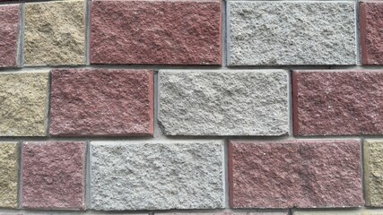 Decorative wall of rectangular stone blocks in warm shades of yellow, gray, and red — textured background for architecture, interior design, and construction renderings