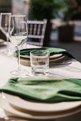 Empty glasses, plates with green napkins on a served festive table.