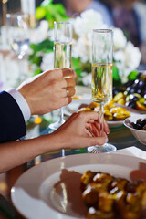 A woman's and man's hands and a glass of champagne on the banquet table.