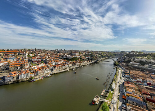 Aerial view of terracotta rooftops cascade towards the Douro River, reflecting the sky under the Dom Lu&Atilde;&shy;s I Bridge, Porto, Porto District, Portugal.