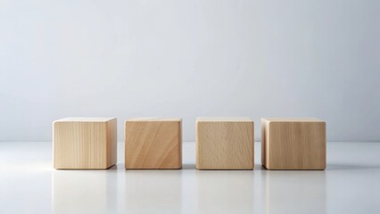 Obraz premium Clean minimal arrangement of four identical light-colored wooden blocks on a bright surface against a neutral backdrop