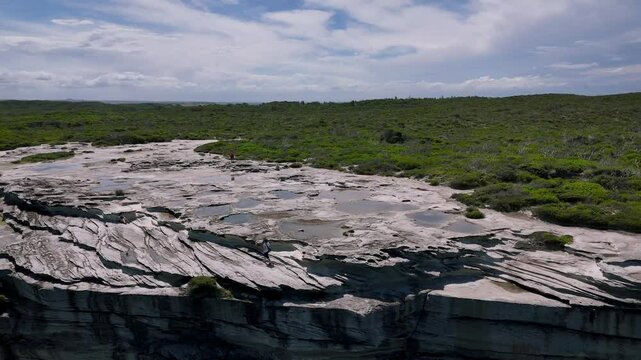 Kurnell, Sydney, Australia -UHD Video: Drone flying over the scenic Cape Baily Track in Kamay National Park. The drone is rotating in a circle, looking down at sandstone cliffs and splashing waves.