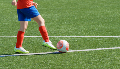 Young soccer player dribbling ball on turf field