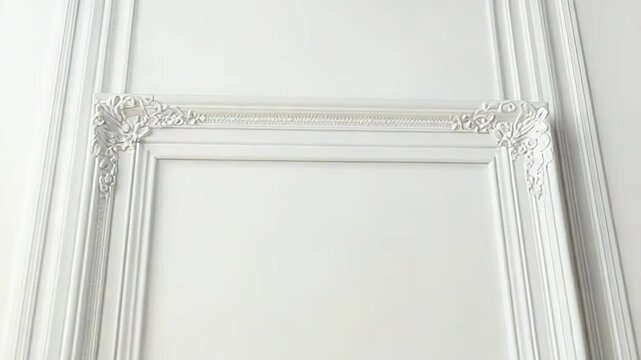 White ornate frame hanging on a white wall with molding