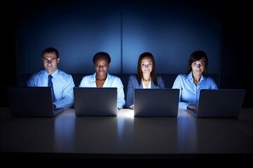 Businesspeople working late at night with laptops.