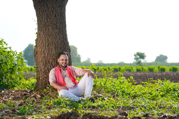 young indian farmer sitting at agricultural field