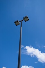 Parking lot lights on a tall pole against a blue sky