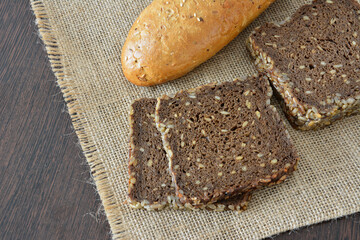 Freshly baked bread and sliced rye bread on a rustic burlap cloth