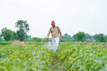 indian farmer spraying pesticide at green field