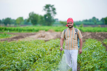 indian farmer spraying pesticide at green field